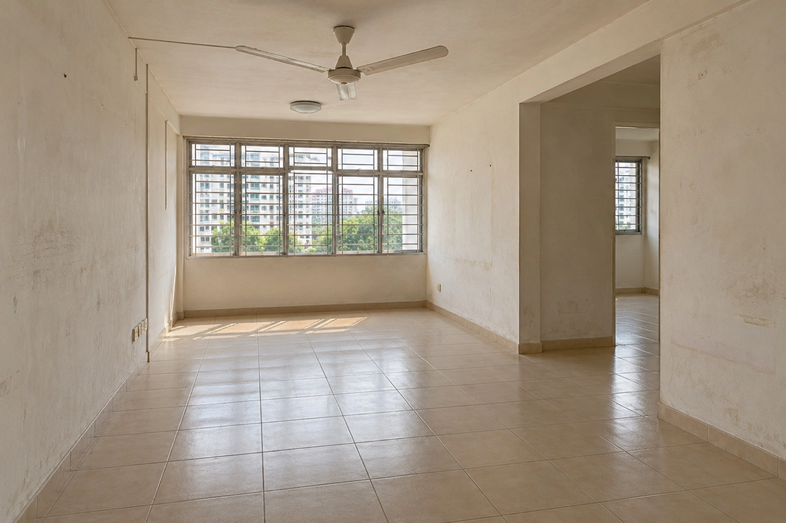 Before: Empty HDB living room with worn walls, beige tiled floor and grille windows. After: Furnished warm plaster living room retaining its beige ceramic floor.